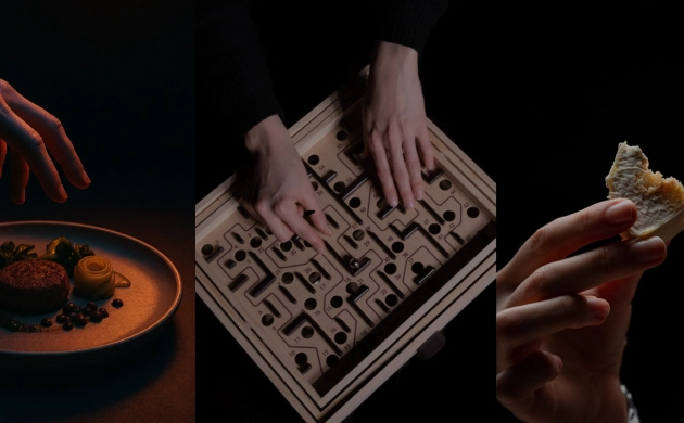 Ambiance sombre illustrant l'expérience Dans le Noir ? : une main tendue vers une assiette gastronomique, des mains guidant une bille dans un jeu de labyrinthe en bois, et une main tenant un morceau de pain près d'une bouche