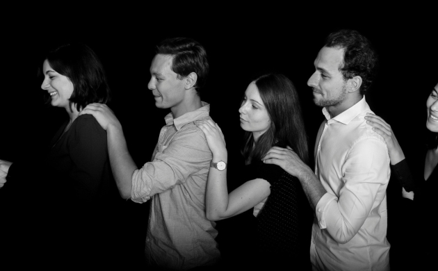 Un groupe de personnes avançant en file indienne, guidé dans l'obscurité, illustrant une expérience immersive de Dans le Noir ?.