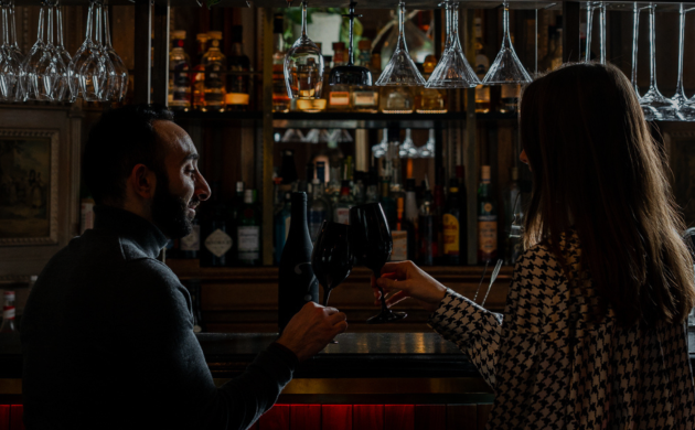 Couple partageant un verre de vin au bar dans une ambiance intimiste, moment convivial avant un dîner au restaurant