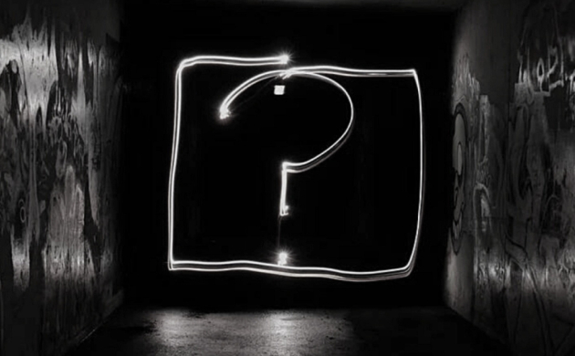 Un point d'interrogation lumineux dessiné dans l'obscurité d'un tunnel, symbolisant mystère et exploration sensorielle.