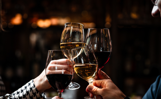 Groupe d’amis trinquant avec des verres de vin rouge et blanc dans une ambiance conviviale et festive.