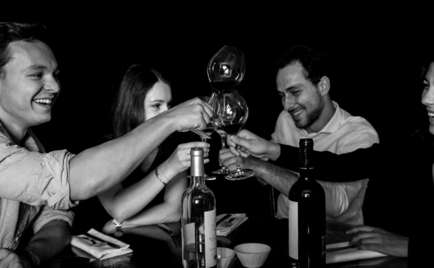 Quatre personnes trinquant avec des verres de vin dans une ambiance immersive et conviviale, illustrant l'expérience sensorielle de Dans le Noir ?